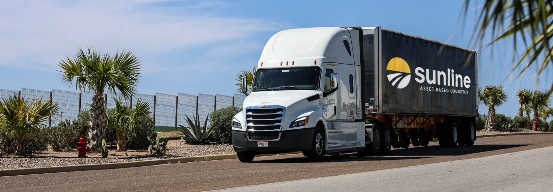 White Sunline tractor with Sunline branded trailer driving through a desert landscape