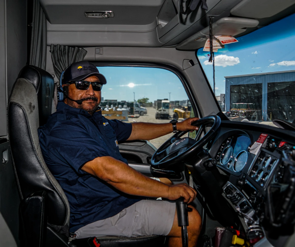 Sunline driver wearing sunglasses seated in the driver seat of a tractor