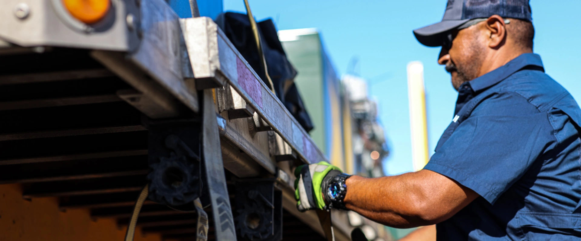 Male Sunline driver securing load straps on a flatbed trailer