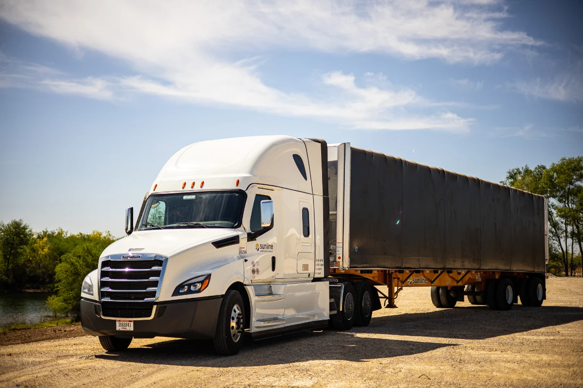 White Sunline Freightliner tractor with Sunline branded trailer driving on a road