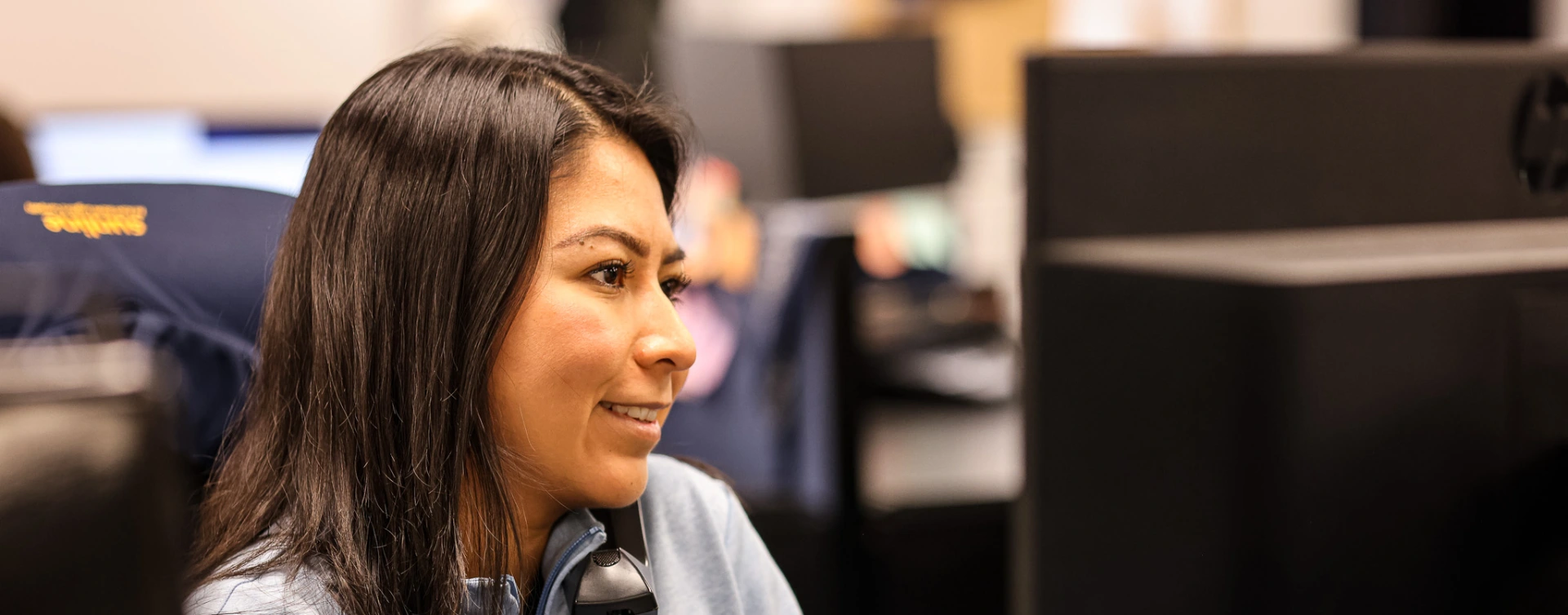 Female Sunline employee smiling at her desk wearing a headset in the office