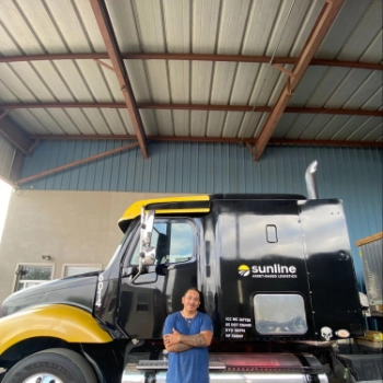 Guillermo Segura, Sunline driver, smiling and leaning against a Sunline tractor with his arms crossed
