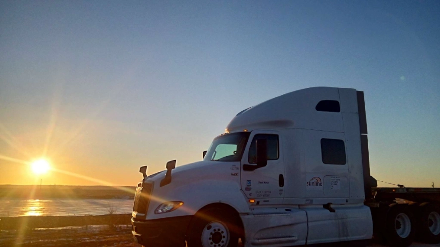 White Sunline tractor truck parked at sunset over open snowy fields