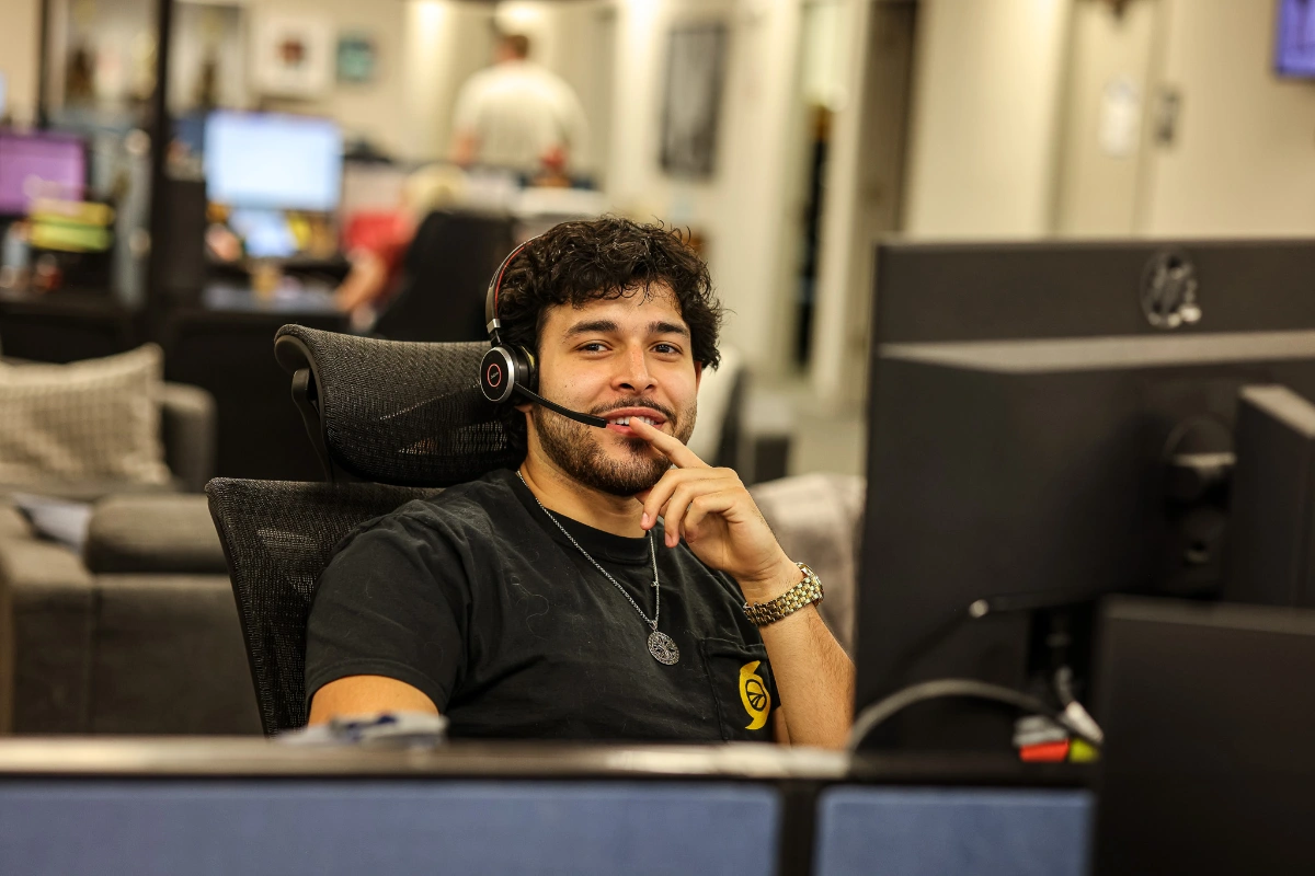 Male Sunline office employee wearing a headset and smiling at his desk