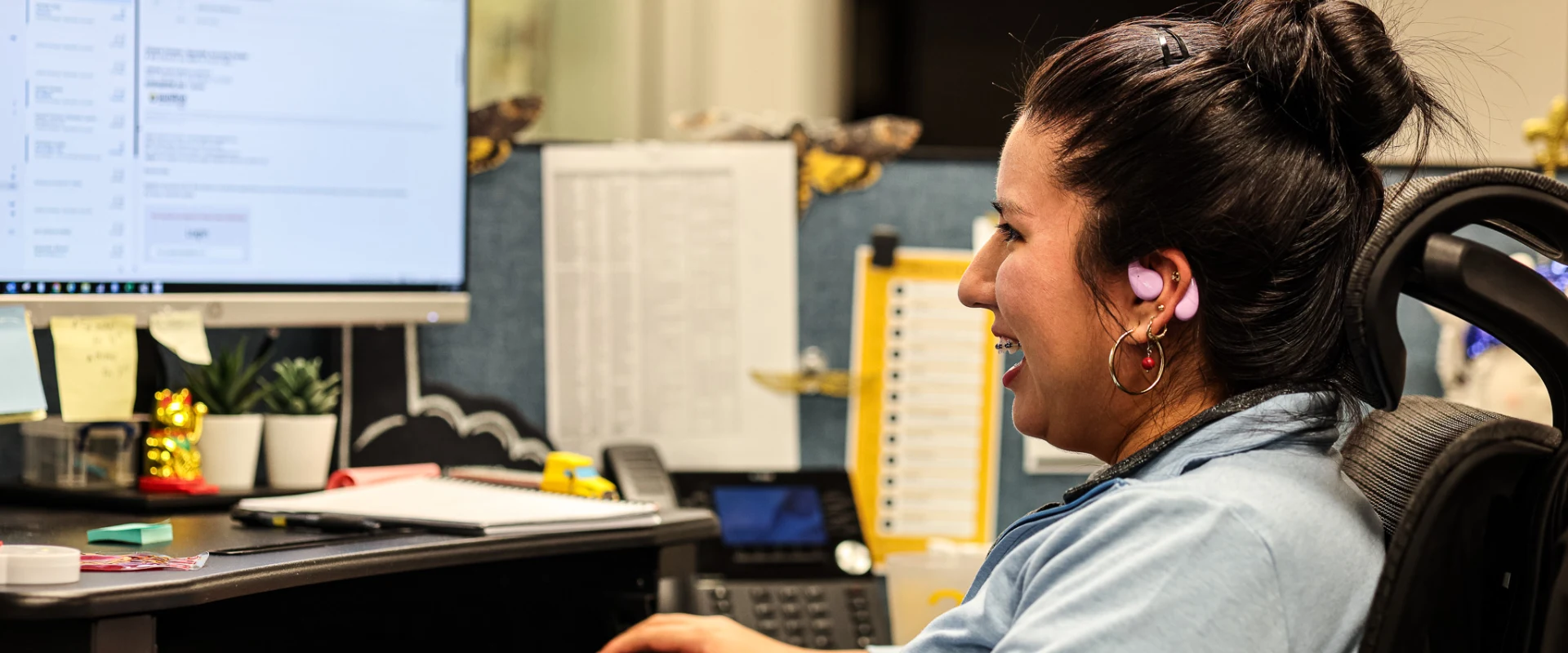 Female Sunline office employee wearing a headset and smiling at her desk